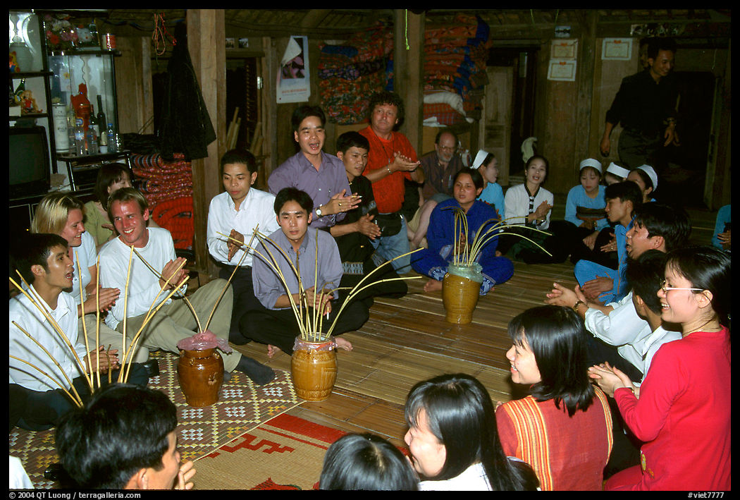 Guests in a thai house gather around jars of rau can alcohol, Ban Lac, Mai Chau. Northwest Vietnam