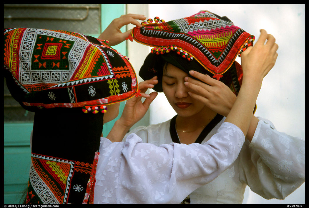 A thai woman helps her friend with her elaborate headdress, Son La. Northwest Vietnam