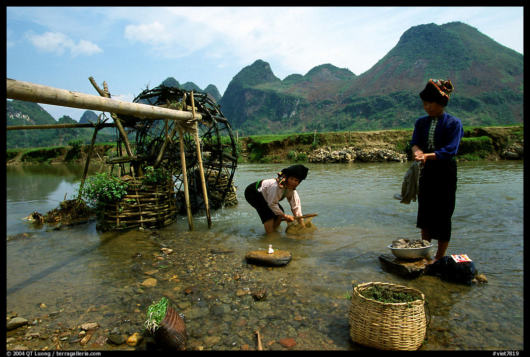 Thai women washing laundry and collecting water plants near an irrigation wheel, near Son La. Northwest Vietnam