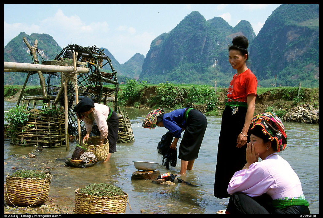 Thai women washing laundry and collecting water plants near an irrigation wheel, near Son La. Northwest Vietnam