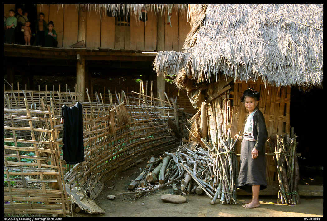Woman in front of her hut and family on stilt house, between Lai Chau and Tam Duong. Northwest Vietnam