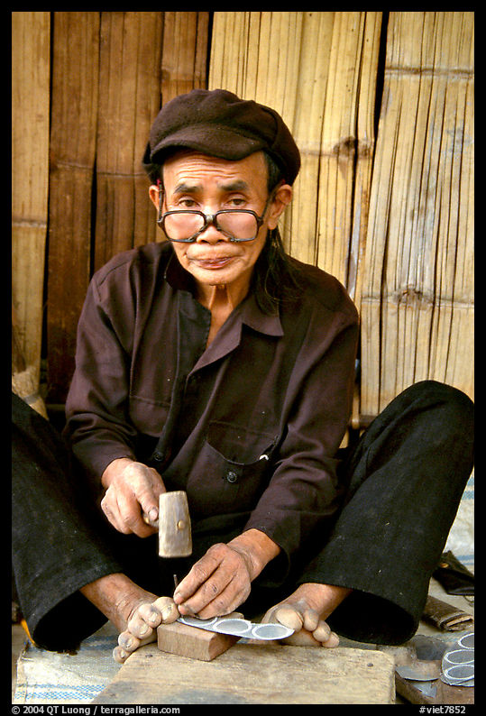 Black Dzao man making the decorative coins used in the children hats, between Tam Duong and Sapa. Northwest Vietnam