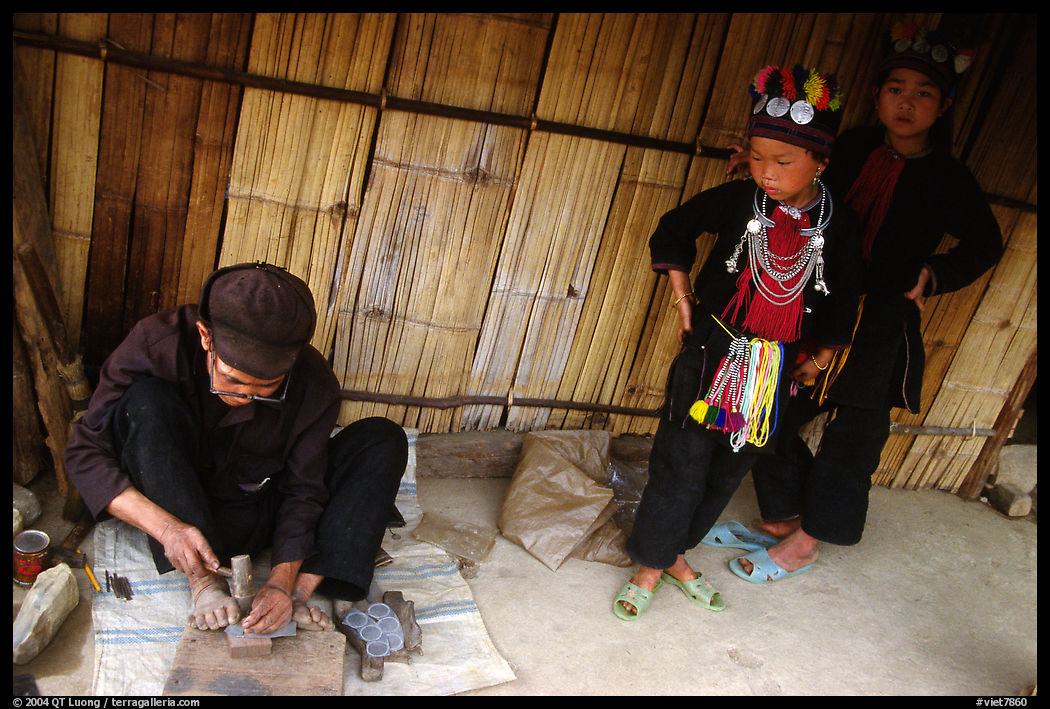 Black Dzao children look at a man  making the decorative coins used on their hats, between Tam Duong and Sapa. Northwest Vietnam
