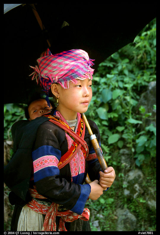 Hmong girl sheltering herself and her younger sibling with an unbrella, between Lai Chau and Tam Duong. Northwest Vietnam