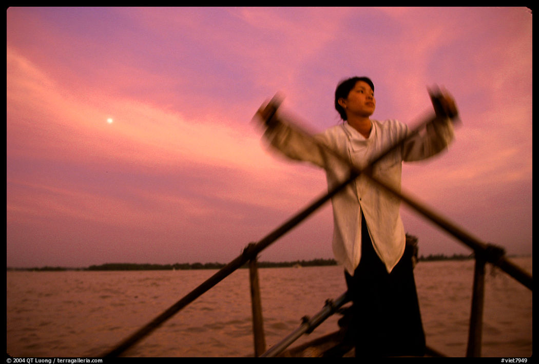 Boater using the X-shaped paddle characteristic of the Delta, sunset. Can Tho, Vietnam