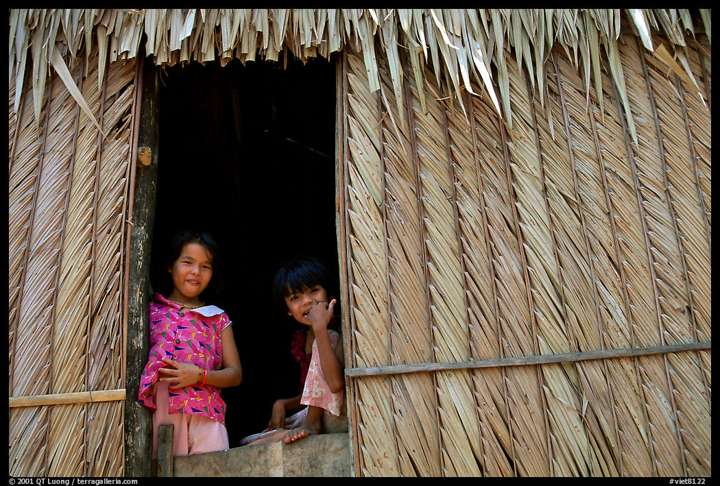 Children pear through a traditional hut. Hong Chong Peninsula, Vietnam