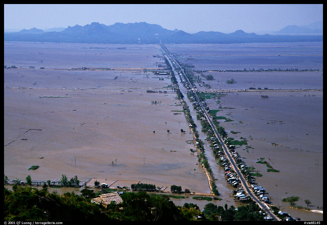 Stilts houses line a road traversing inundated rice fields, seen from Sam mountain. Cambodia is in the far. Chau Doc, Vietnam