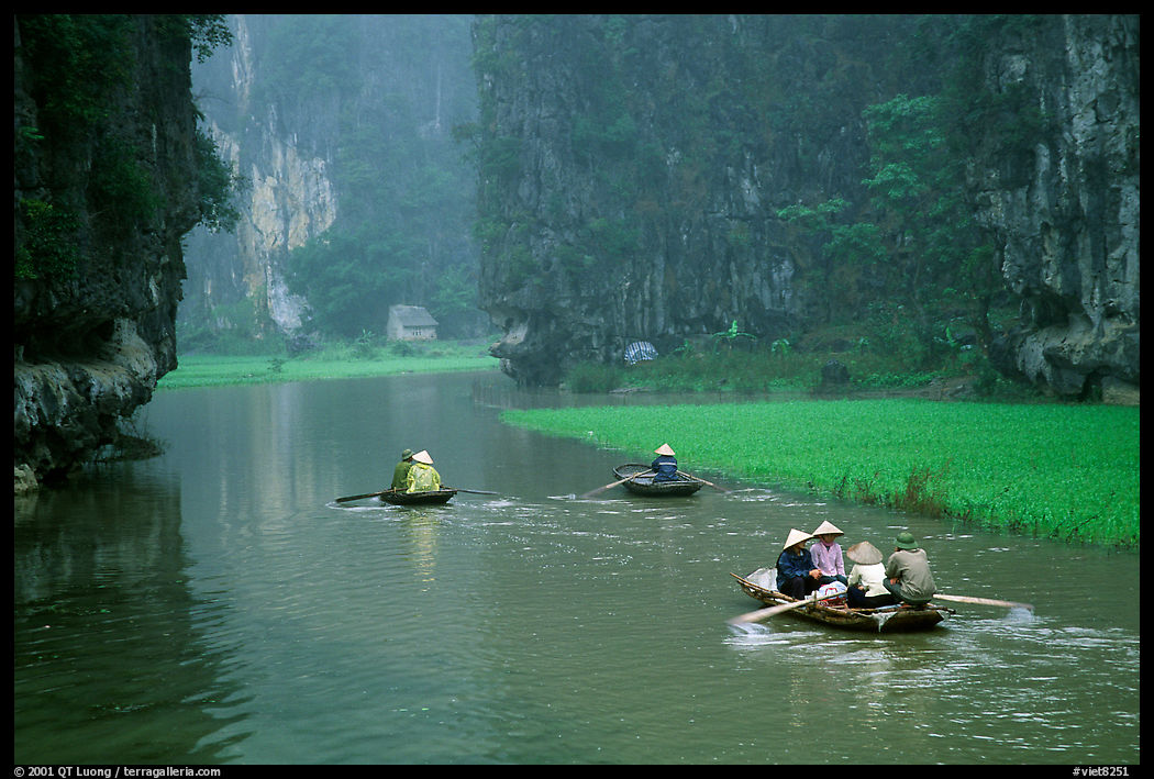 Villagers go to work floating a shallow river in Tam Coc. near Ninh Binh,  Vietnam