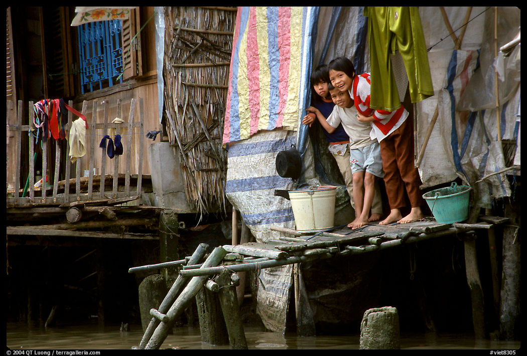 Children peering from their waterfront house. Can Tho, Vietnam