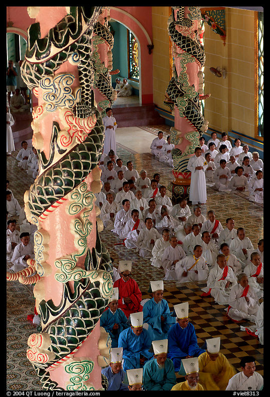 Priests and ornate columns inside the Great Caodai Temple. Tay Ninh, Vietnam