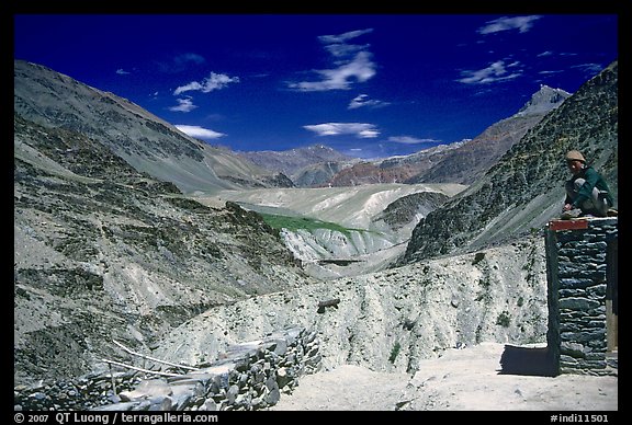 Woman sitting on roof of house in front of mountain landscape, Zanskar, Jammu and Kashmir. India