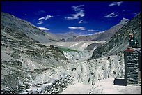 Woman sitting on roof of house in front of mountain landscape, Zanskar, Jammu and Kashmir. India (color)