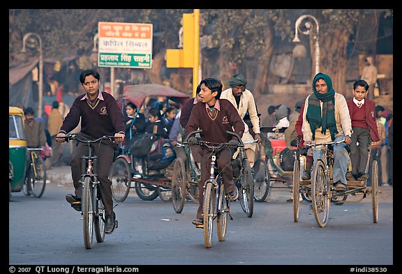 Children riding bikes in rickshaws on way to school. New Delhi, India (color)