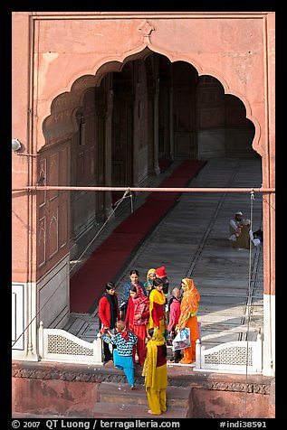 Women standing beneath arched entrance of prayer hall, Jama Masjid. New Delhi, India