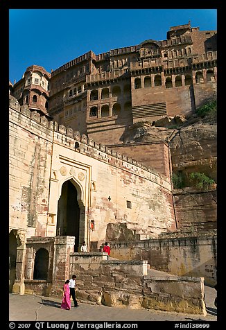 Couple walking below gate and high walls, Mehrangarh Fort. Jodhpur, Rajasthan, India