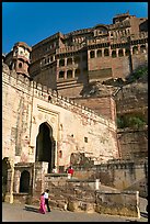 Couple walking below gate and high walls, Mehrangarh Fort. Jodhpur, Rajasthan, India (color)