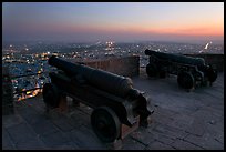 Cannons on top of Mehrangarh Fort, and city lights and dusk. Jodhpur, Rajasthan, India (color)