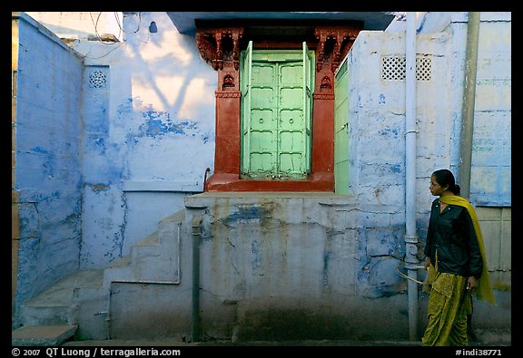 Woman walks infront of blue tinted whitewashed wall. Jodhpur, Rajasthan, India