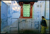 Woman walks infront of blue tinted whitewashed wall. Jodhpur, Rajasthan, India