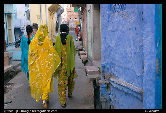 Women walking in narrow alley with blue walls. Jodhpur, Rajasthan, India