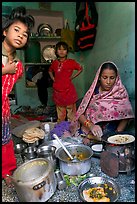 Woman cooking, flanked by two girls. Jodhpur, Rajasthan, India