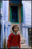 Schoolgirl standing in front of a house with blue tint. Jodhpur, Rajasthan, India