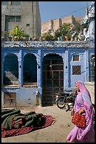 Woman in sari, blue house, and fort in the distance. Jodhpur, Rajasthan, India (color)