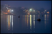 Rowboats and reflected lights on the Ganges River at dusk. Varanasi, Uttar Pradesh, India