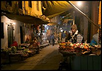 Flower vendor in  narrow old city alley at night. Varanasi, Uttar Pradesh, India