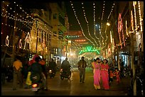 Women walking in street with illuminations. Varanasi, Uttar Pradesh, India