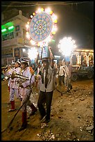 Uniformed musicians and men carrying lights during wedding procession. Varanasi, Uttar Pradesh, India