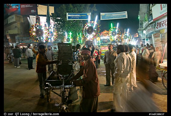 Men pulling generator on bicycle to power lights during wedding procession. Varanasi, Uttar Pradesh, India (color)