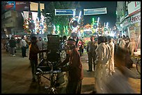 Men pulling generator on bicycle to power lights during wedding procession. Varanasi, Uttar Pradesh, India (color)