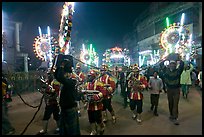 Musicians, men carrying lights, and carriage during wedding procession. Varanasi, Uttar Pradesh, India