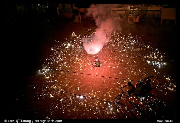 Man firing fireworks in middle of street ahead of wedding procession. Varanasi, Uttar Pradesh, India (color)