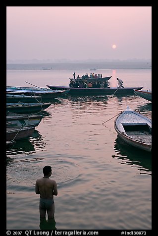 Man standing in Ganga River and boats at sunrise. Varanasi, Uttar Pradesh, India