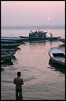 Man standing in Ganga River and boats at sunrise. Varanasi, Uttar Pradesh, India