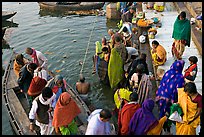 Hindu pilgrims walk out of boat onto Dasaswamedh Ghat. Varanasi, Uttar Pradesh, India (color)