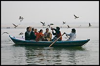 Indian tourists on rawboat surrounded by birds. Varanasi, Uttar Pradesh, India