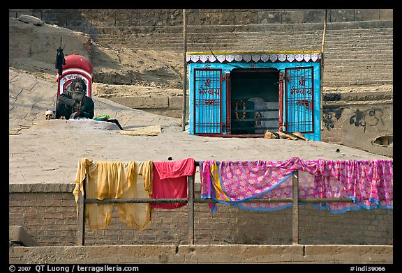 Sadhu sitting next to shrine and laundry. Varanasi, Uttar Pradesh, India (color)