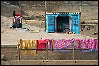 Sadhu sitting next to shrine and laundry. Varanasi, Uttar Pradesh, India (color)