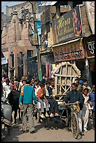 Man moving devotional image and children on rickshaw. Varanasi, Uttar Pradesh, India (color)