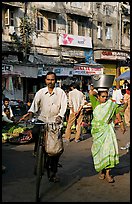 Man riding bike and woman with basket on head, Colaba Market. Mumbai, Maharashtra, India (color)