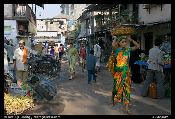 Women carrying  baskets on head in narrow street, Colaba Market. Mumbai, Maharashtra, India (color)