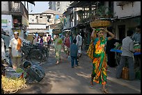 Women carrying  baskets on head in narrow street, Colaba Market. Mumbai, Maharashtra, India