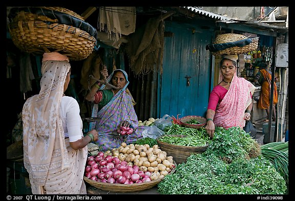 Women with baskets on head buying vegetables, Colaba Market. Mumbai, Maharashtra, India