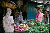 Women with baskets on head buying vegetables, Colaba Market. Mumbai, Maharashtra, India