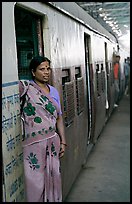 Woman standing at door of suburban train. Mumbai, Maharashtra, India