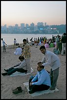 Head masseurs and Mumbai skyline at sunset,  Chowpatty Beach. Mumbai, Maharashtra, India