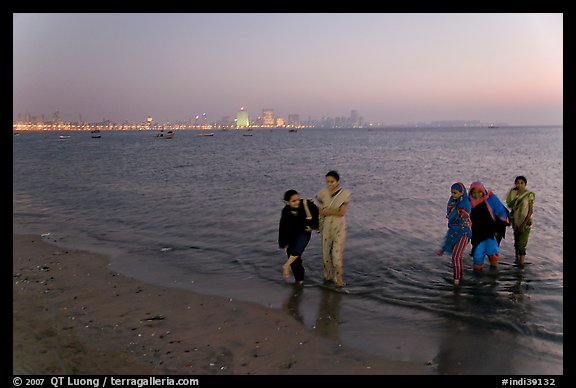 Women walking in water by night, Chowpatty Beach. Mumbai, Maharashtra, India (color)